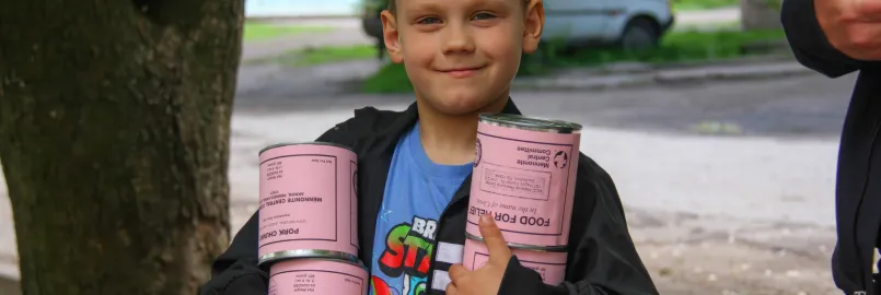 A boy* holds cans of meat he and his mother (not pictured) received from volunteers with MCC partner Association of Mennonite Brethren Churches of Ukraine (AMBCU). The canned meat was part of a distri